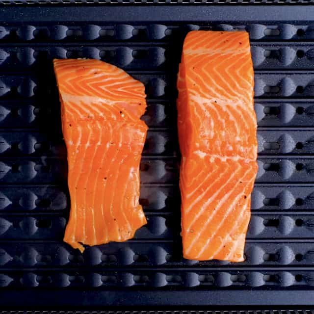Salmon fillets being cooked on an indoor grill.