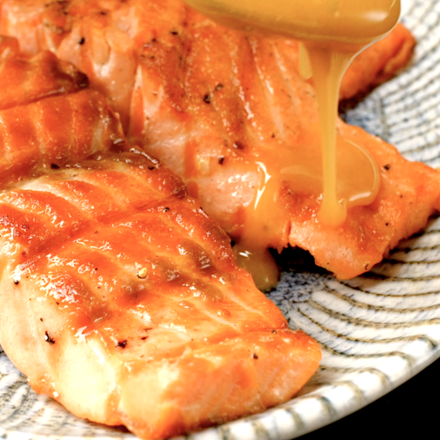 Honey-lime glazed being drizzled over freshly grilled salmon to make honey glazed salmon recipe.