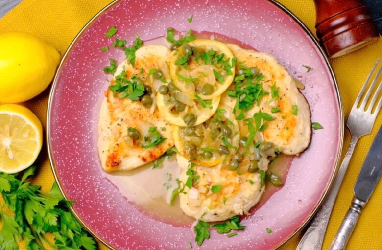Chicken piccata on a plate with lemons and capers