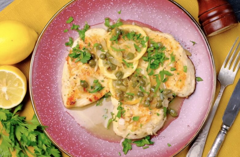 Chicken piccata on a plate with lemons and capers