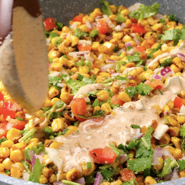 Dressing being added on homemade Mexican street corn salad before serving.