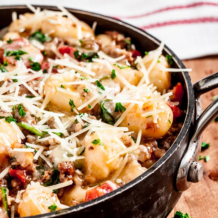 Gnocchi with sausage, spinach, and tomatoes in a pan
