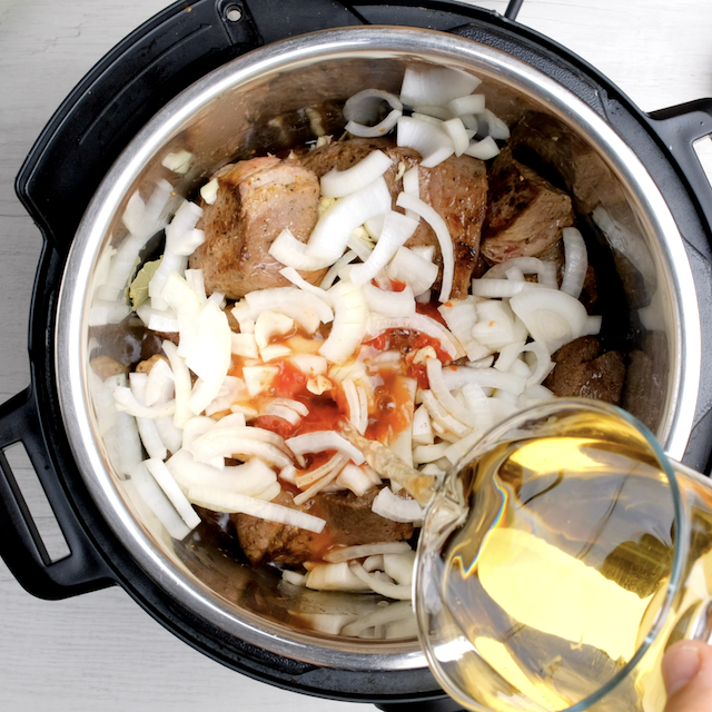 Broth being added to an instant pot with seared beef and aromatics to make roast beef.