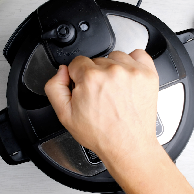 A hand closing the lid of an instant pot to make instant pot roast beef.