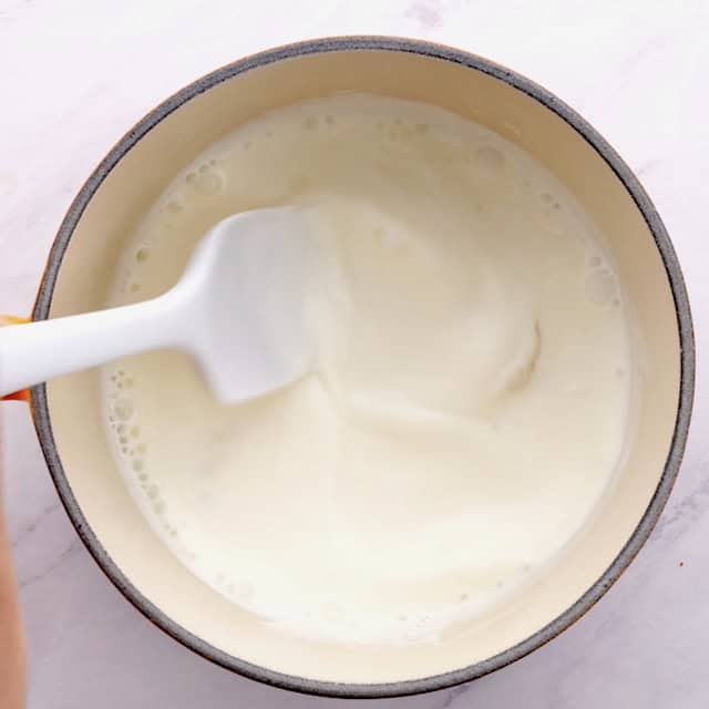 White chocolate being melted in cream-gelatin mixture to make triple chocolate mousse cake top layer.