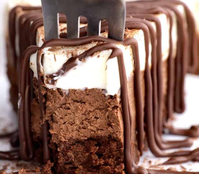 A fork being inserted into a slice of triple chocolate mousse cake.