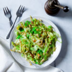 Stir Fry Cabbage with Olive oil and garlic on white plate with forks