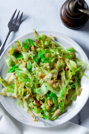 Stir Fry Cabbage with Olive oil and garlic on white plate with forks