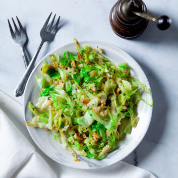 Stir Fry Cabbage with Olive oil and garlic on white plate with forks