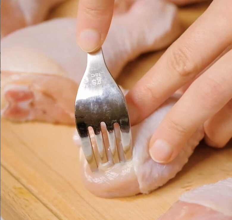 poking holes in pieces of chicken.