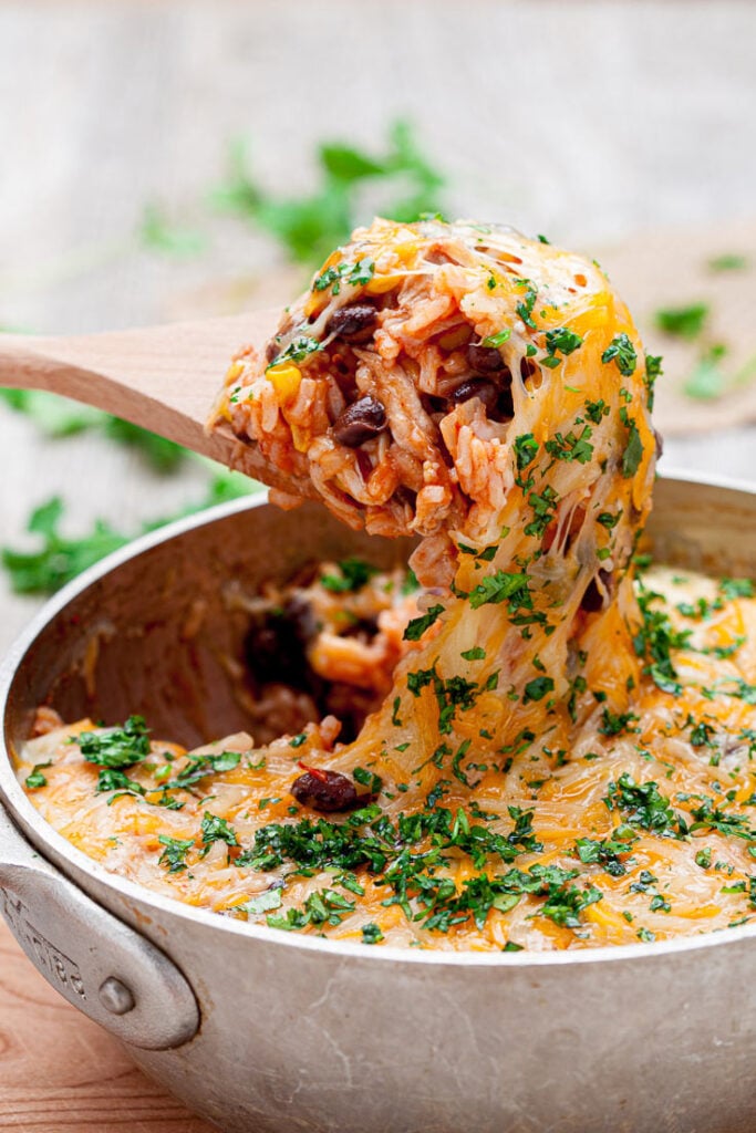 chicken enchilada casserole in a pot with wooden spoon