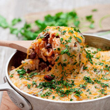 chicken enchilada casserole with rice in a pot with wooden spoon