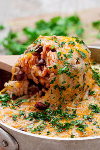 chicken enchilada casserole with rice in a pot with wooden spoon