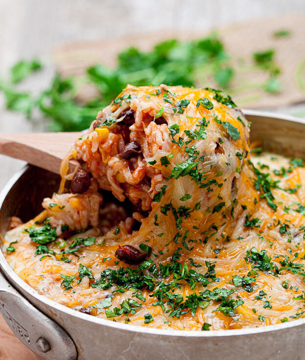 chicken enchilada casserole with rice in a pot with wooden spoon