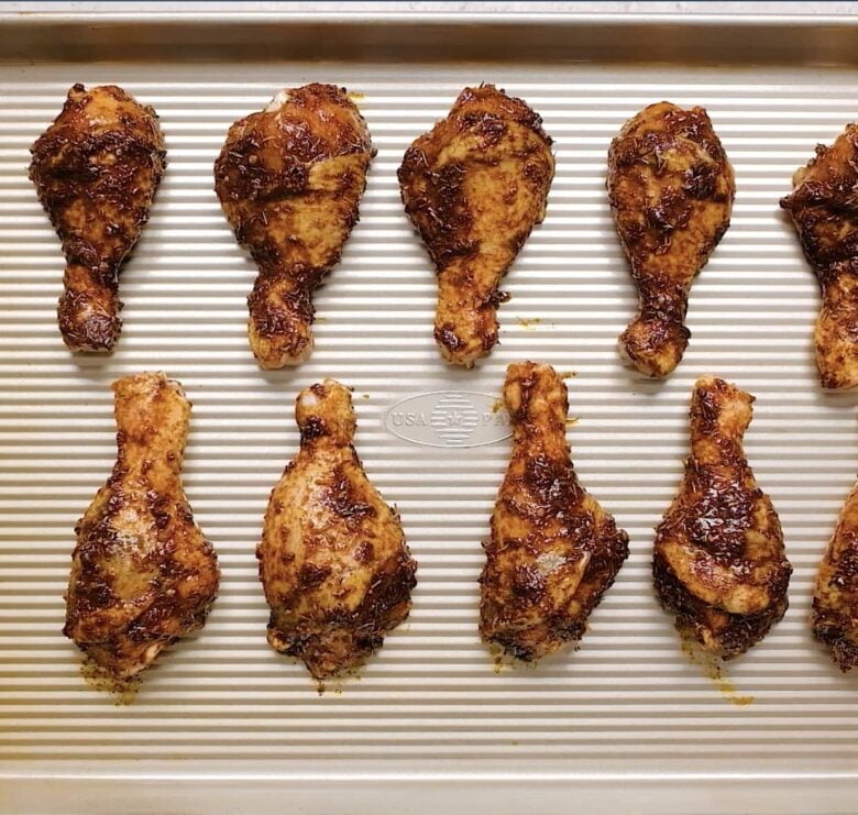 jerk chicken legs on a baking sheet.