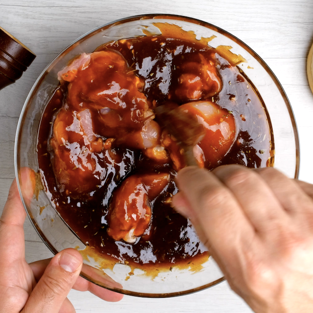 Chicken being added to sauce mixture to make bbq pulled chicken at home.