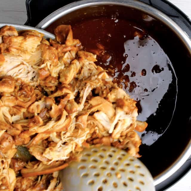 Shredded chicken being returned back to slow cooker with bbq pulled chicken sauce to finish cooking.