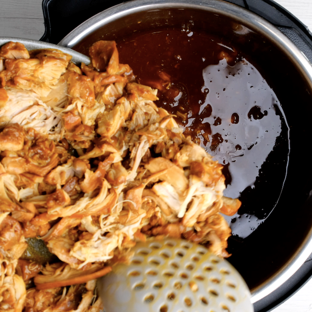 Shredded chicken being returned back to slow cooker with bbq pulled chicken sauce to finish cooking.