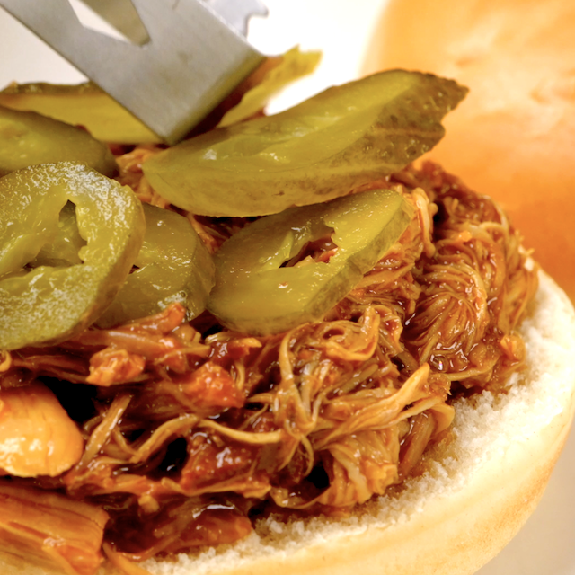 BBQ pulled chicken sandwich being assembled.