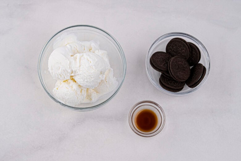 Three bowls with ice cream, Oreo cookies, and vanilla extract that is needed to make the Copycat DQ Blizzard recipe.
