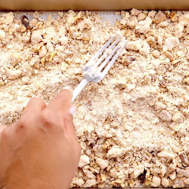 Peach crisp topping being spread on a baking sheet.