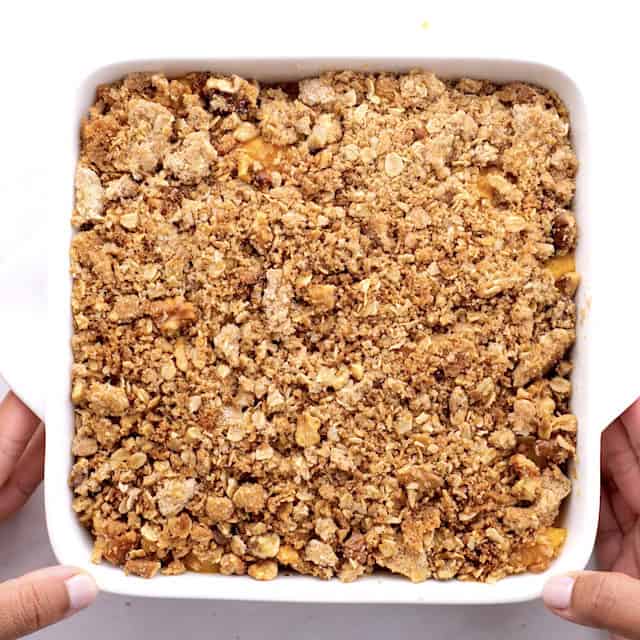 Assembled peach crisp in a baking dish ready to be baked.