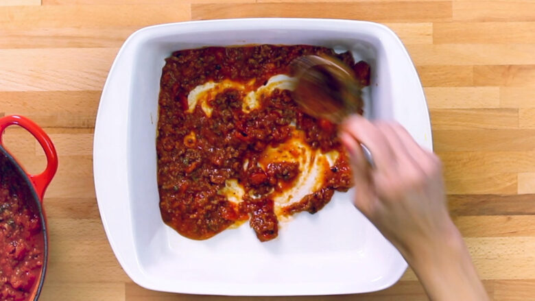 white dish with meat sauce for easy ravioli bake.