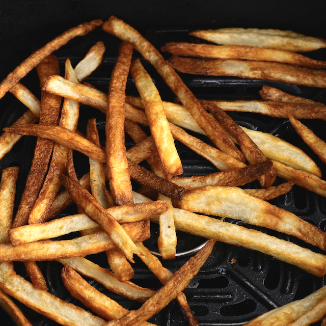 Golden brown extra crispy French fries in an air fryer basket