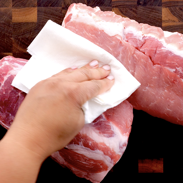 Baby back ribs being patted dry with a paper towel.
