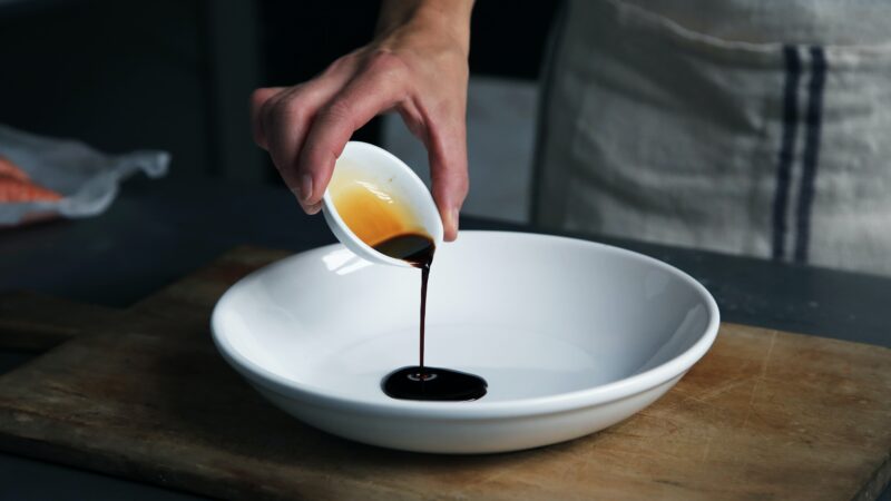 pouring tamari sauce into a white bowl