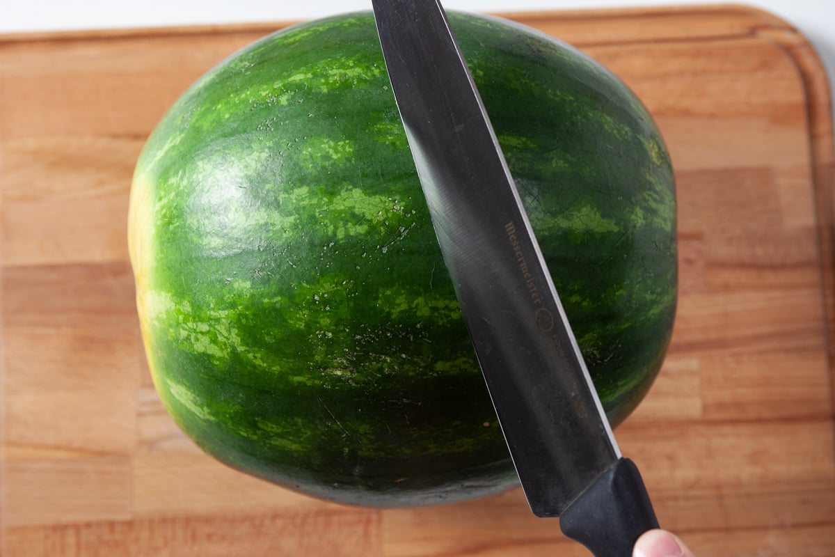 whole watermelon being sliced in half