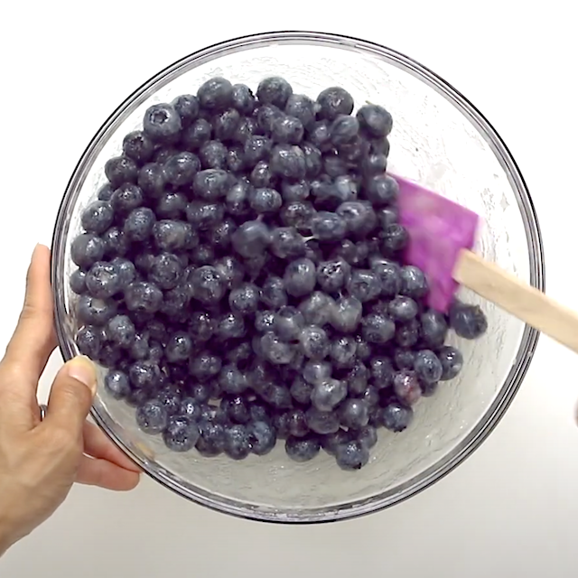 Blueberry filling being prepared in a glass bowl to make blueberry crumb bars.