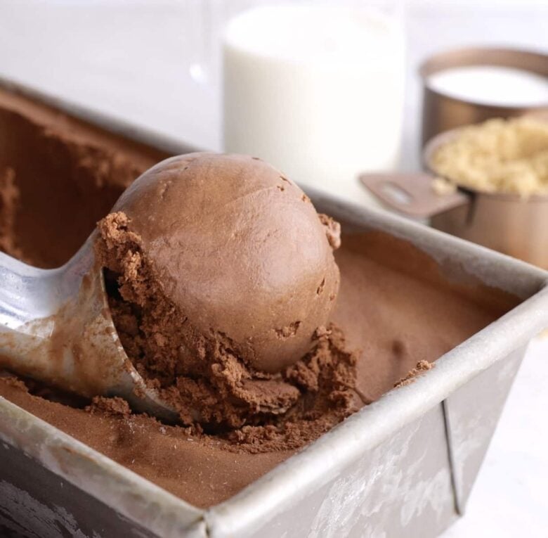 Homemade Chocolate ice cream being scooped out from container. 