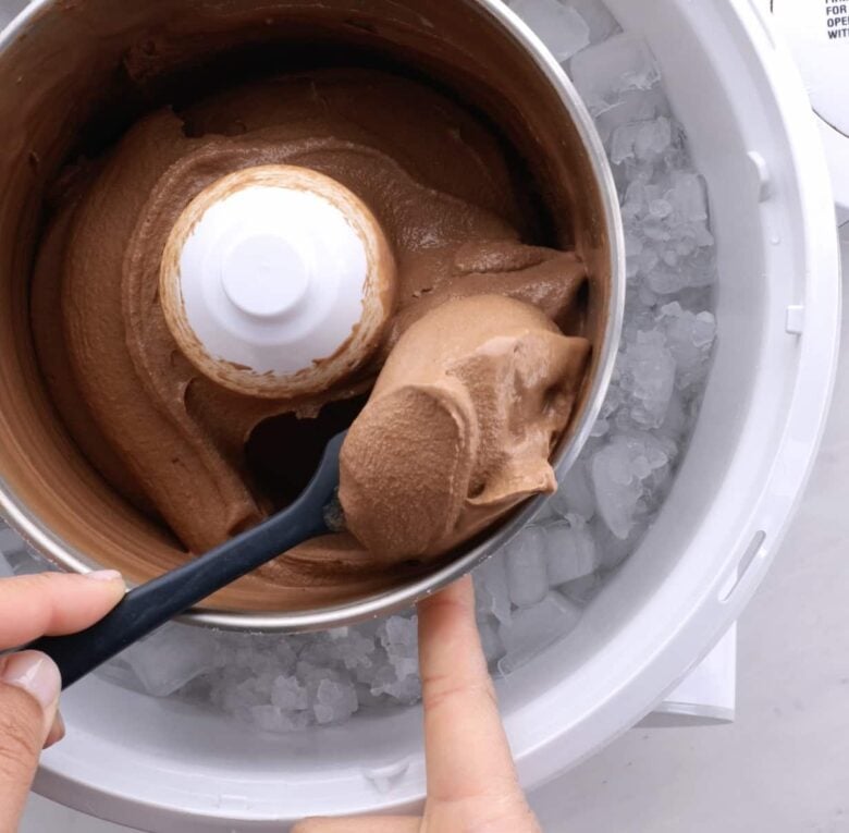 Chocolate ice cream being scooped out from ice cream maker. 