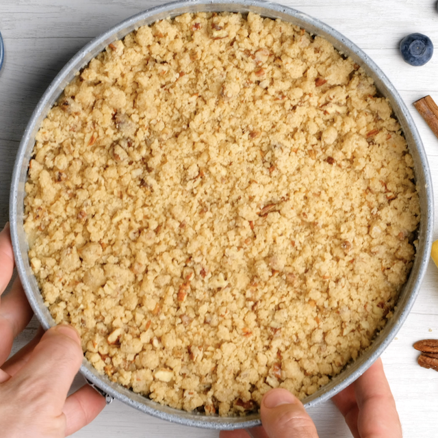 Streusel topping on top of blueberry coffee cake batter, ready to be baked.