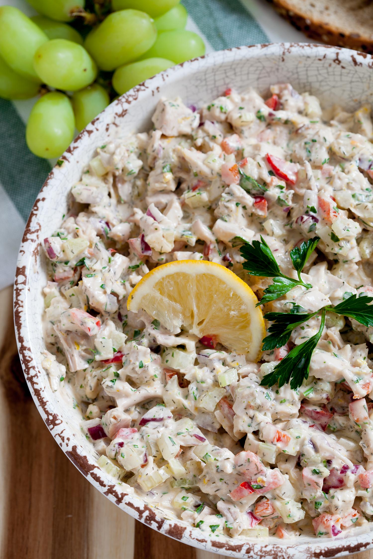 close up image of healthy chicken salad in a bowl with a lemon wedge on top