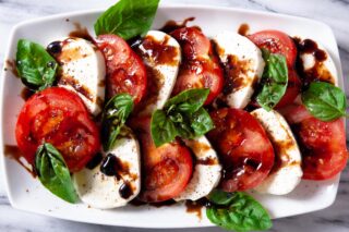 caprese salad topped with balsamic on a white plate