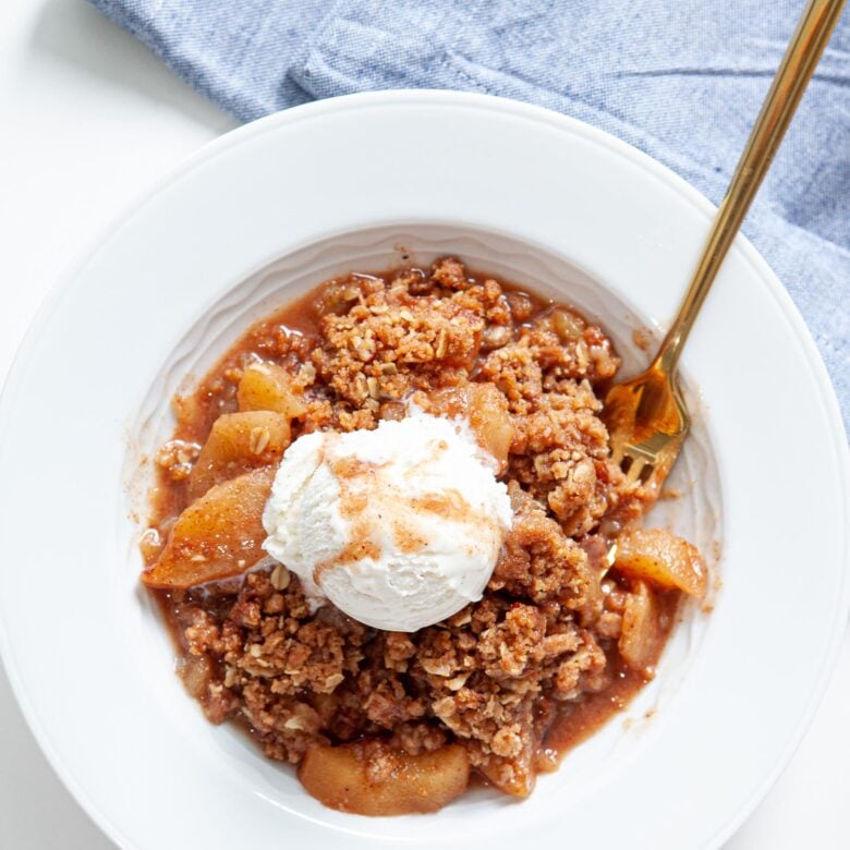 gluten free apple crisp in white bowl with ice cream