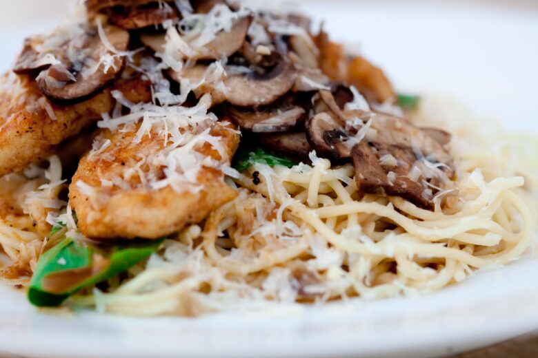 chicken marsala on top of angel hair pasta topped with sliced mushrooms and Parmesan cheese