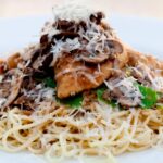 chicken marsala in a white bowl with angel hair pasta