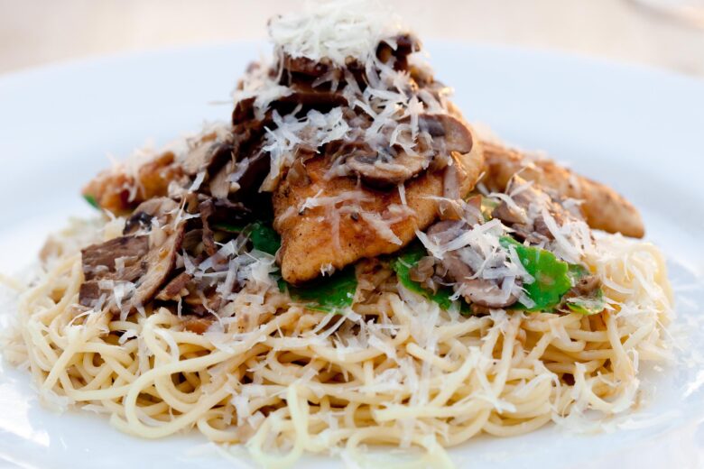 chicken marsala in a white bowl with angel hair pasta