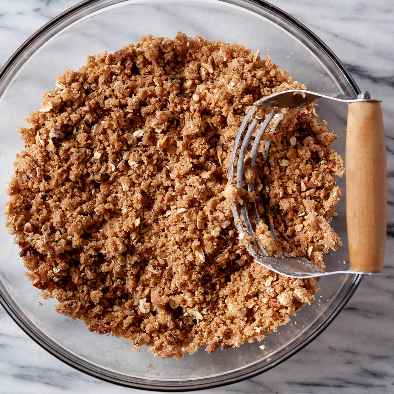 gluten free apple crisp topping in a glass bowl with a pastry cutter on the side