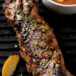 grilled pork tenderloin with peach bbq sauce in the background