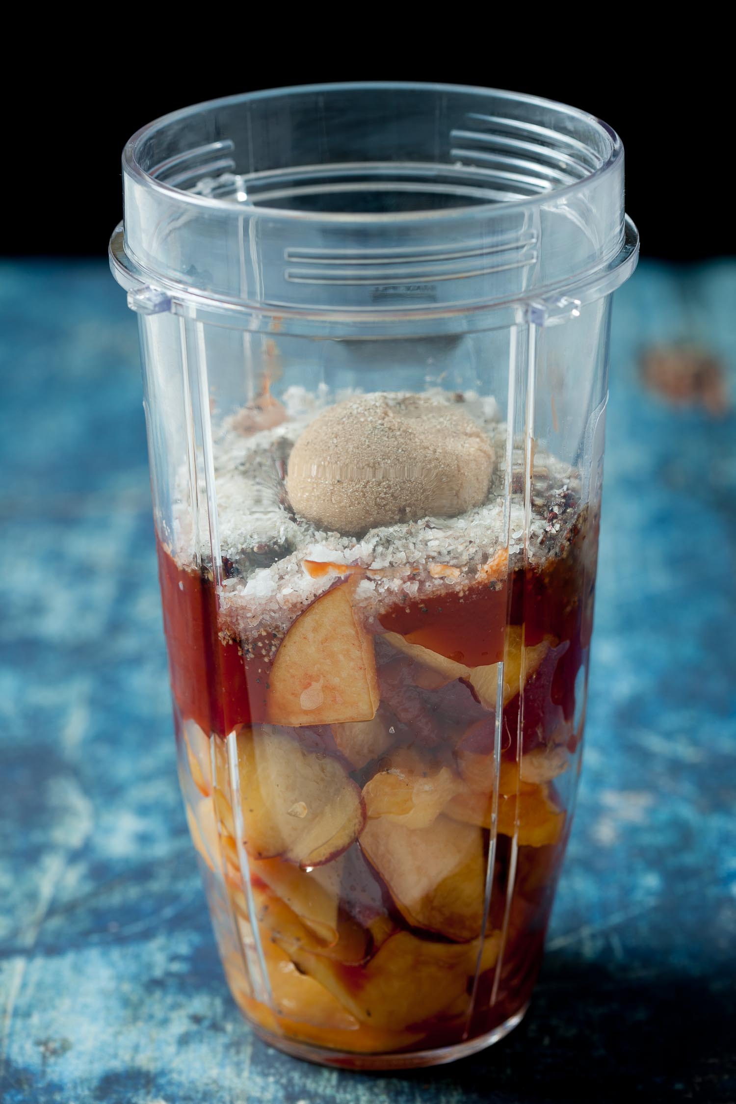 a blender cup full of peaches, honey, mustard, ketchup, salt, and pepper