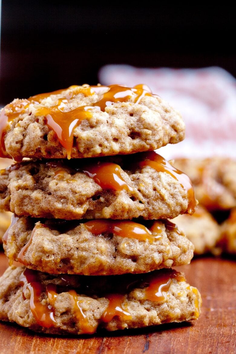 a stack of apple cookies with drizzled caramel and a glass of milk