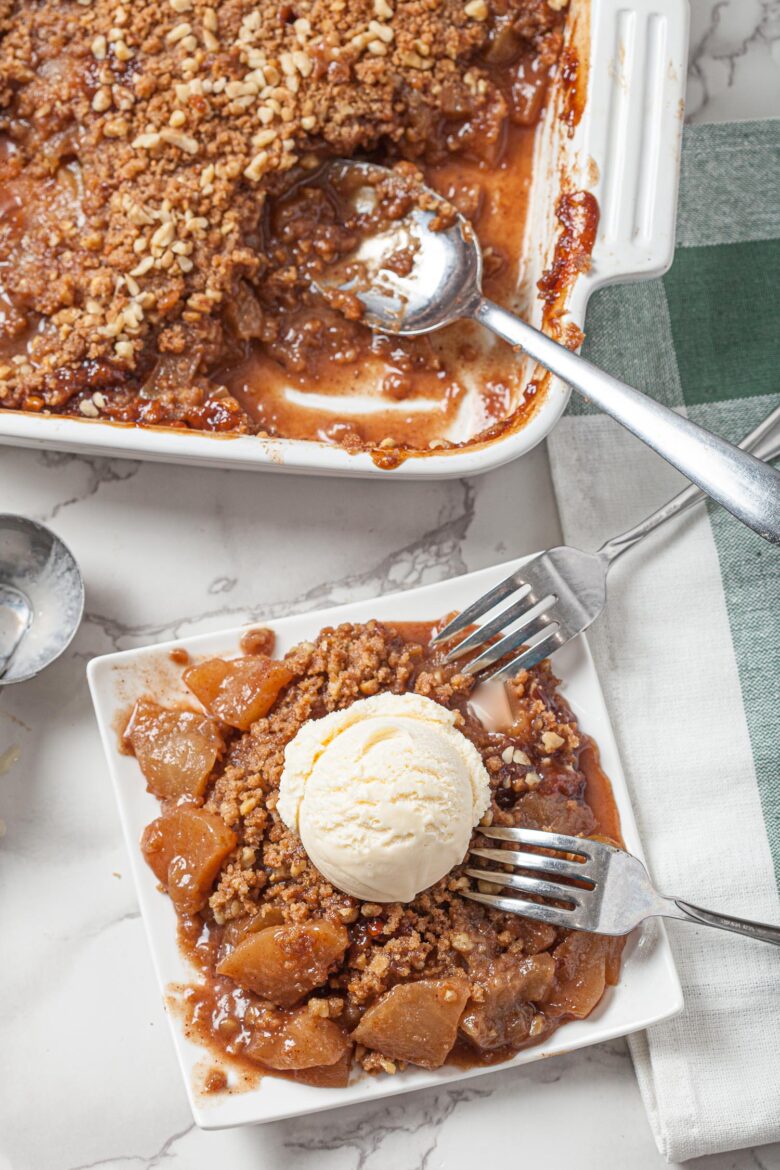 easy apple crisp with crispy pecan oat topping with vanilla ice and two forks