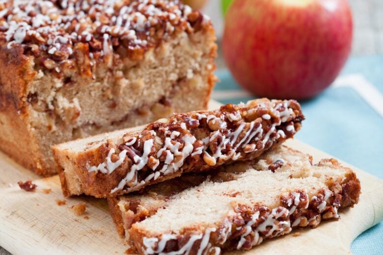 sliced apple bread with streusel topping made with pecans and cinnamon on top of a cutting board