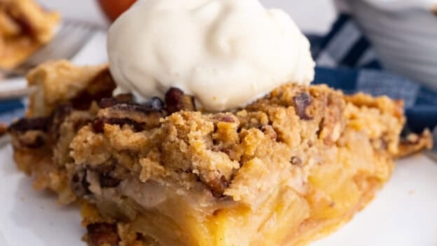 Slice of Dutch Apple Pie Recipe on a white plate with a scoop of vanilla ice cream on top.