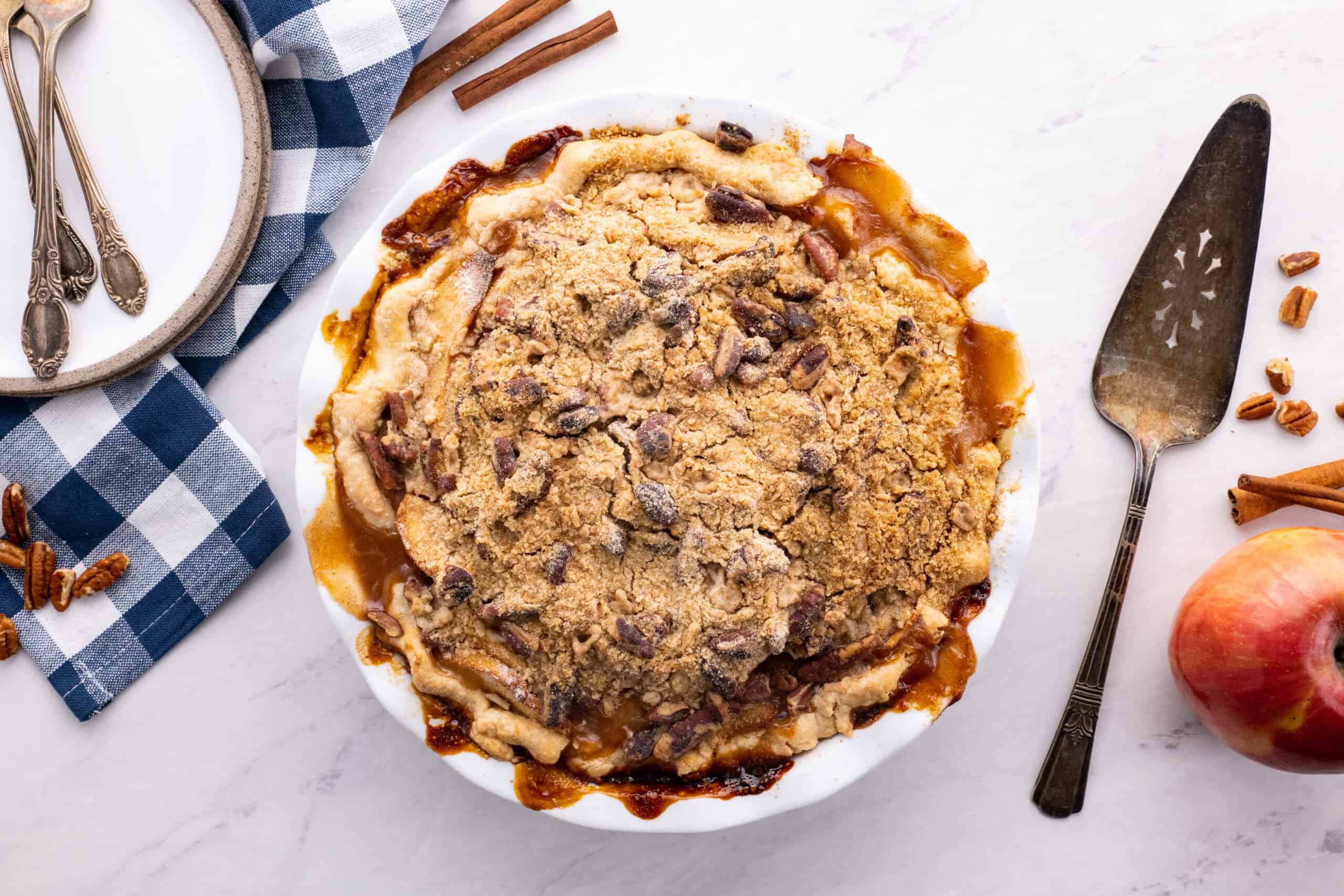 Overhead view looking down of Dutch apple pie in a pie plate with a pie server next to it.