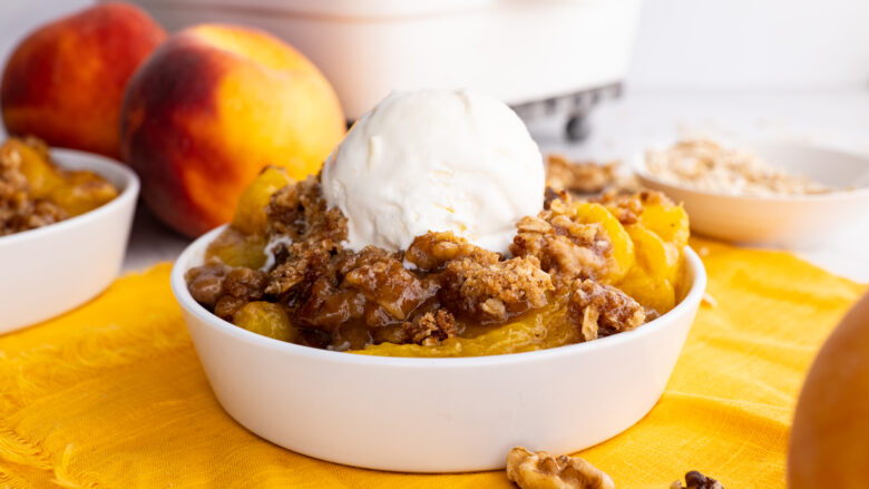 peach crisp in a dish with vanilla ice cream